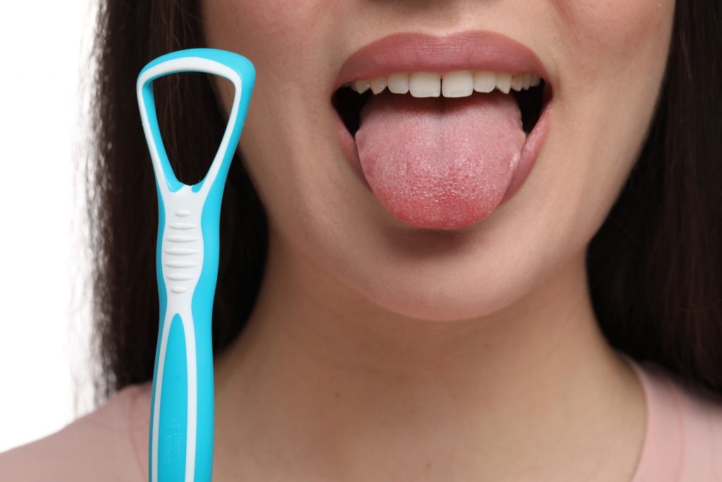 Woman with tongue cleaner on white background, closeup